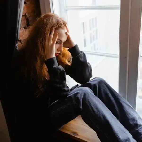 Woman experiencing stress sitting by window, seeking counselling support for anxiety.